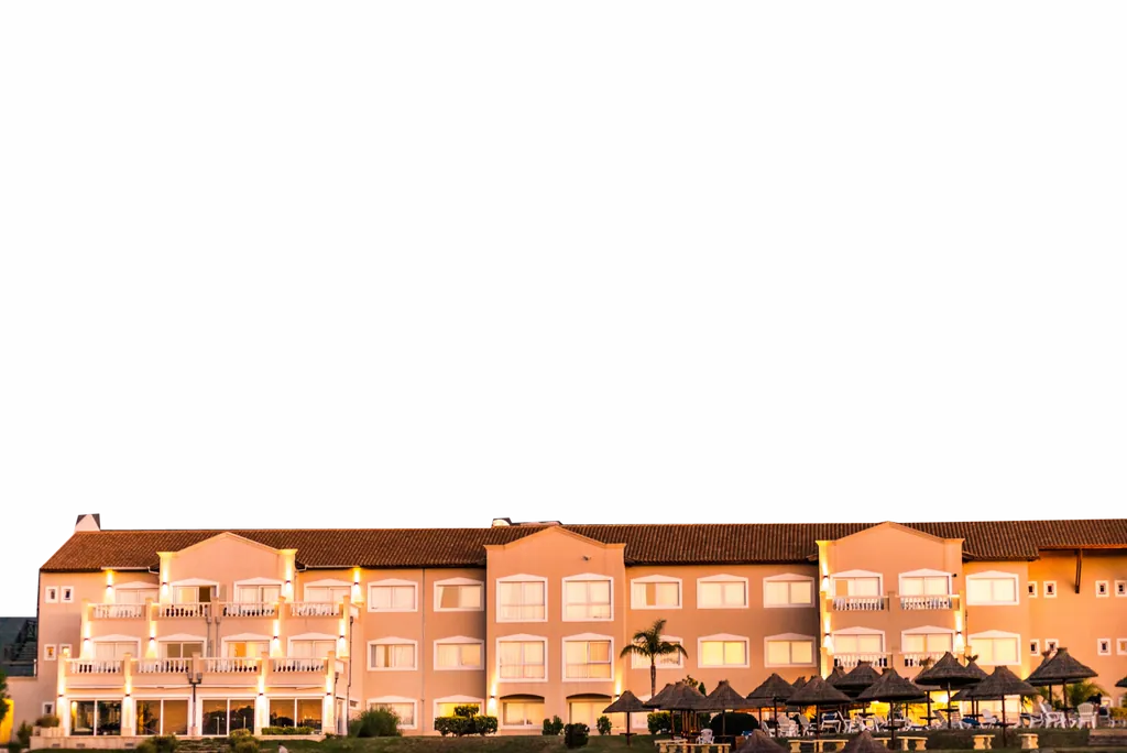 Fachada del Howard Johnson Merlo iluminada al amanecer, con las sierras detrás