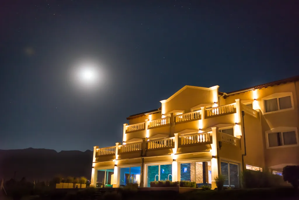 El hotel de noche, con la luna sobre la fachada iluminada